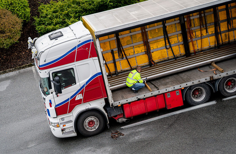 A truck with a person inside who is inspecting steel